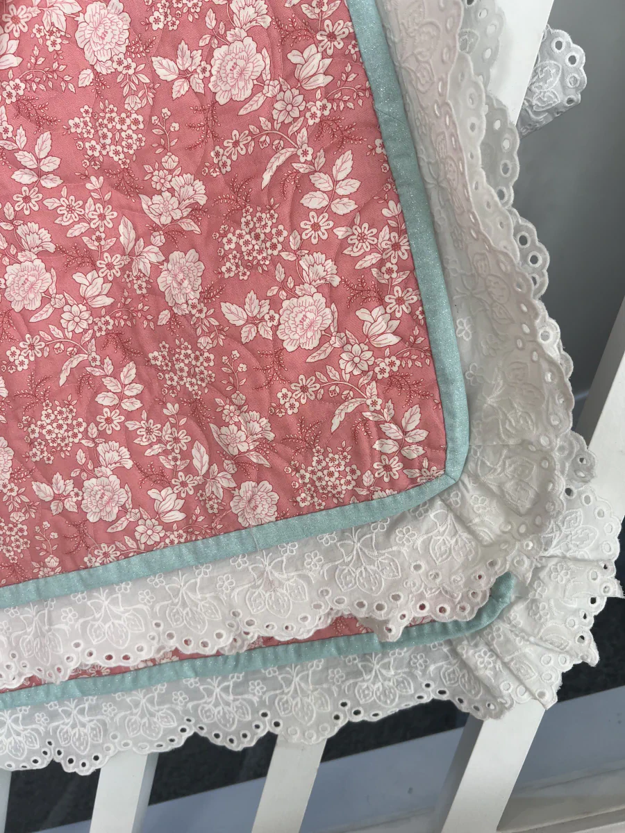 Pink floral quilt backing with turquoise binding and white embroidered lace